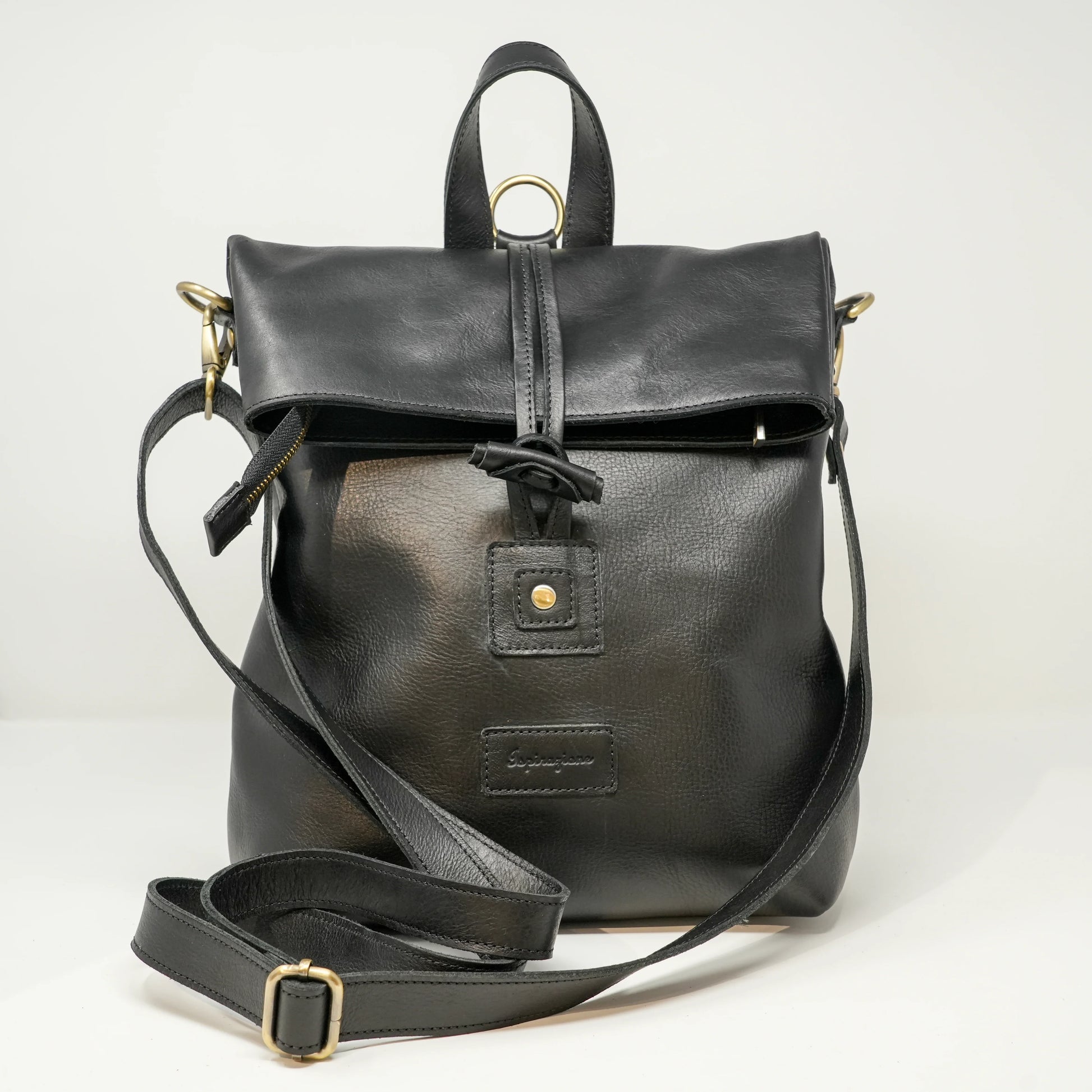 Borsa zaino in pelle nera con chiusura a laccio e cerniera , manico superiore e tracolla regolabile. Accessori metallici dorati e dettaglio con bottone anteriore.